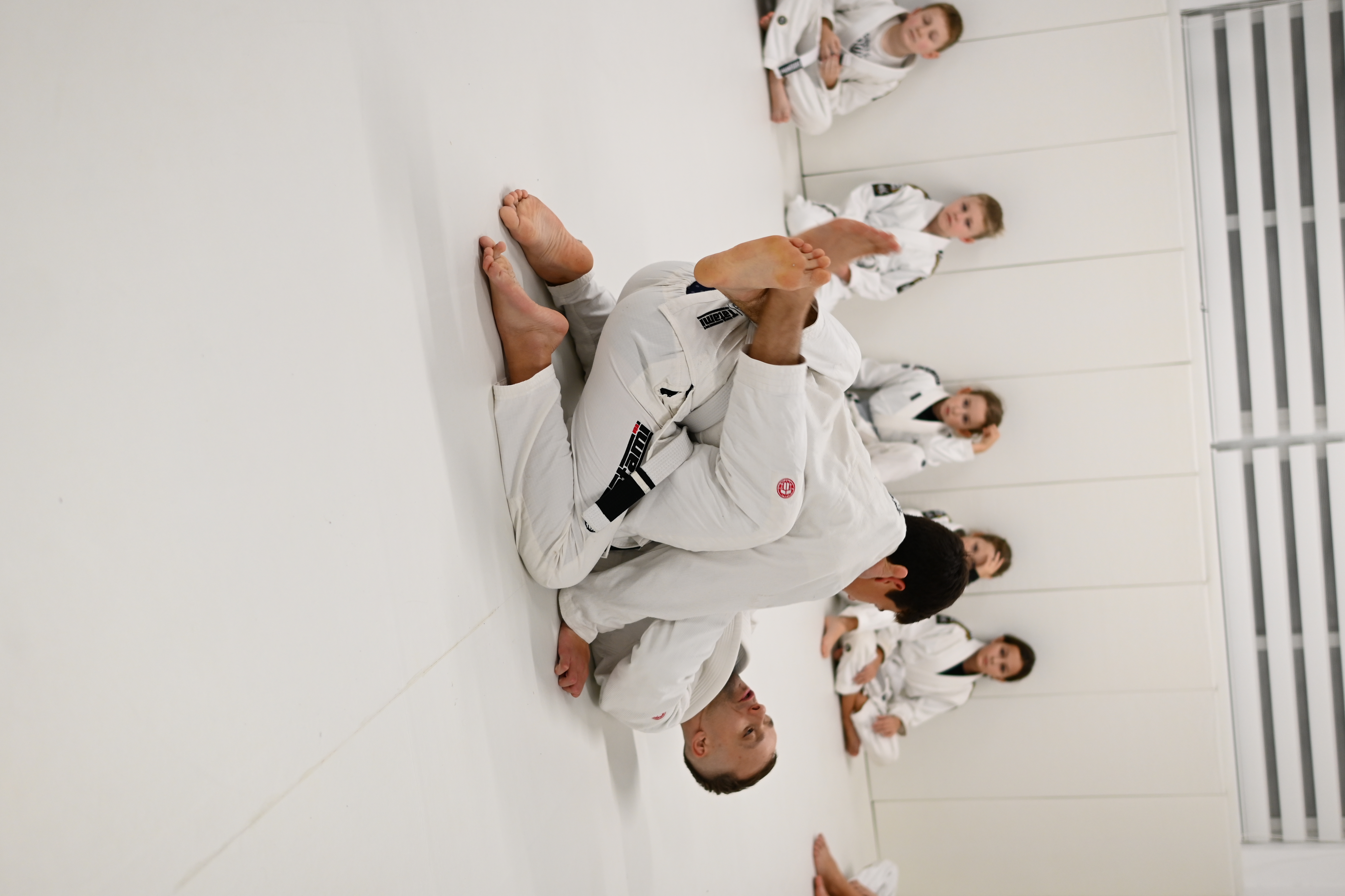 Coach demonstrating armbar with kids watching