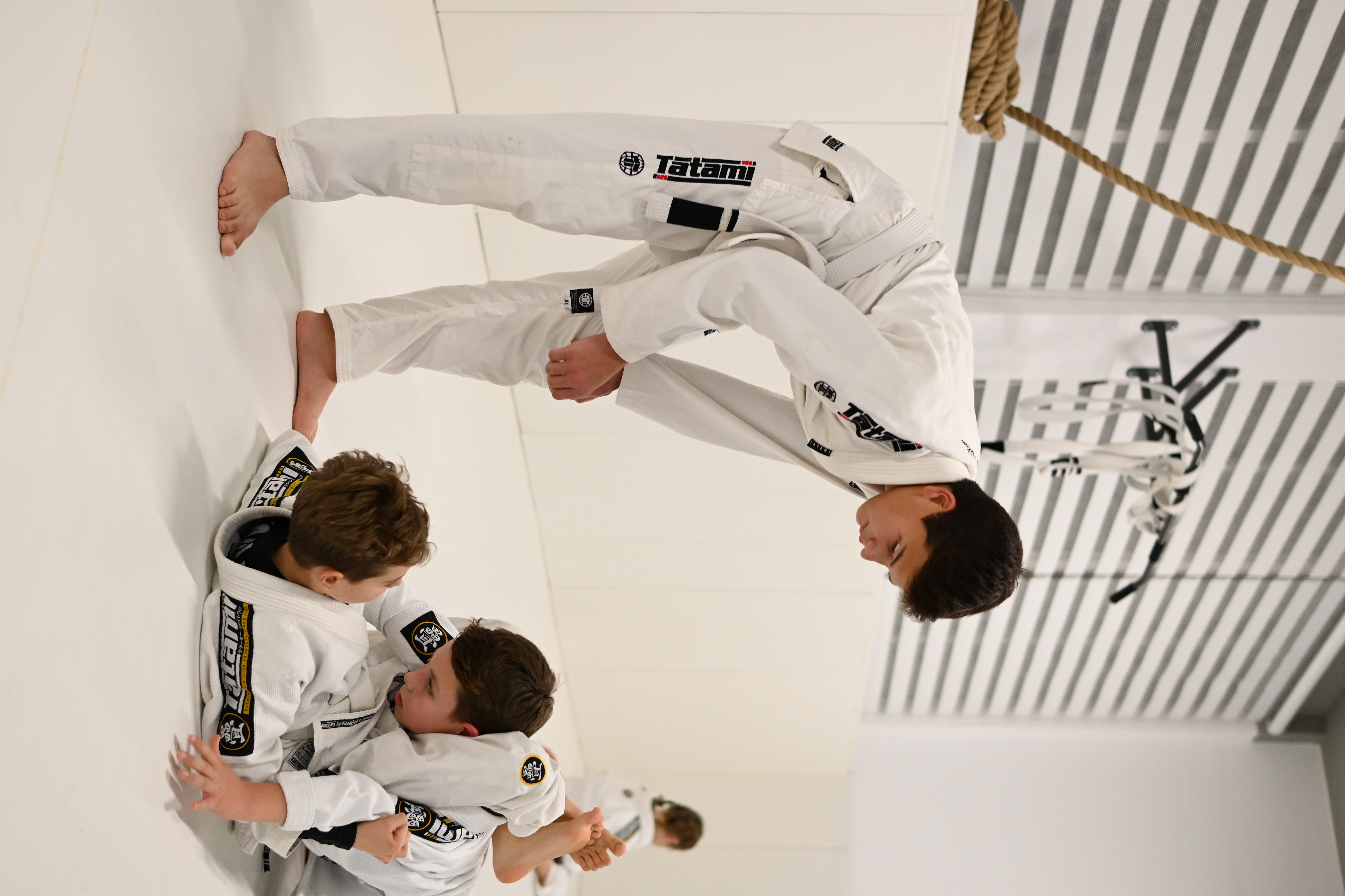 Young coach guiding kids on the mat